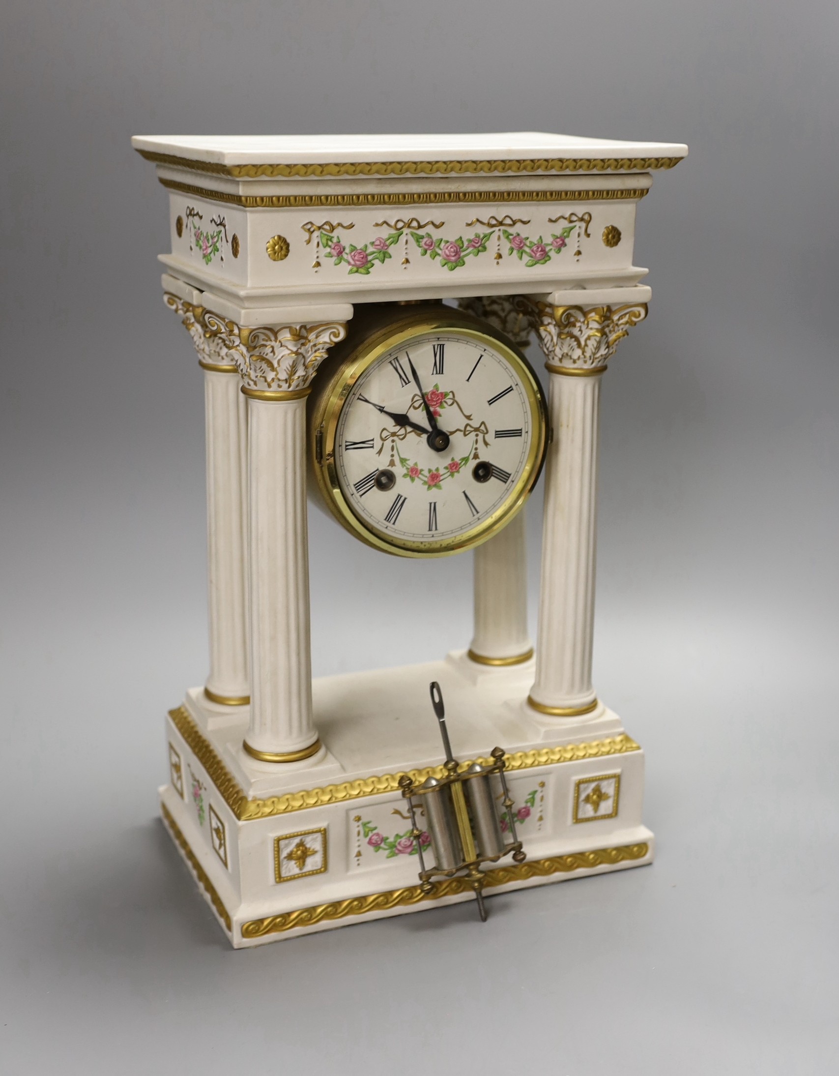 A modern ceramic portico column clock with floral and gilt decoration, with key and pendulum, 37cm tall